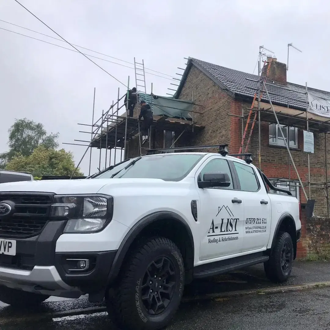 A-List Roofing's branded vehicle outside a scaffolded roofing project in Surrey