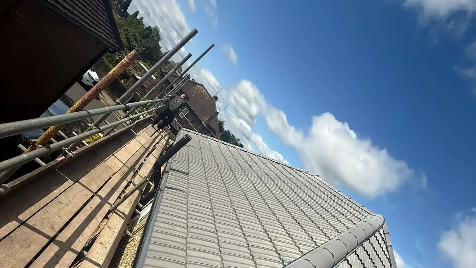 A-List Roofing roofer completing a new tiled roof on a scaffolded property in Surrey